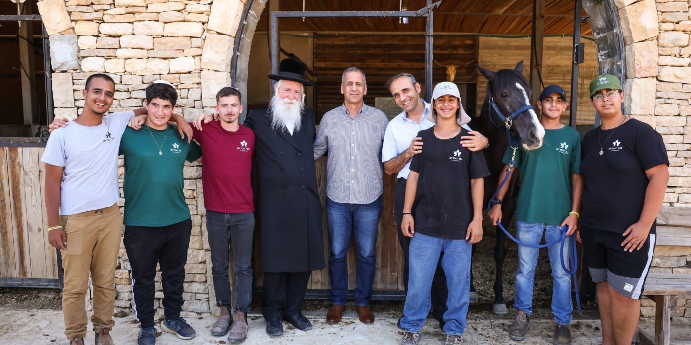 אביב כוכבי עם תלמידי הכפר על רקע חוות הסוסים