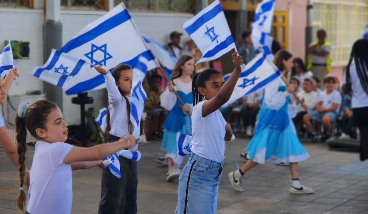 תלמידות רוקדות עם דגלי ישראל