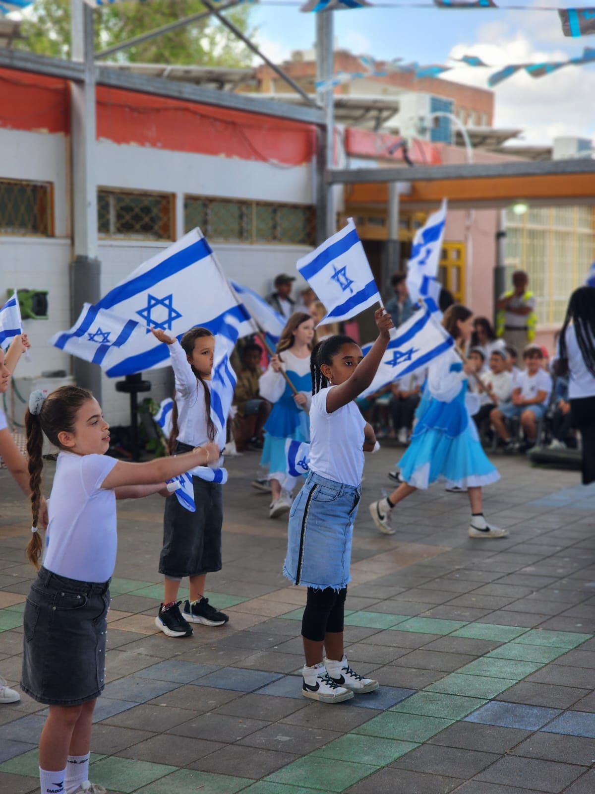 תלמידות רוקדות עם דגלי ישראל