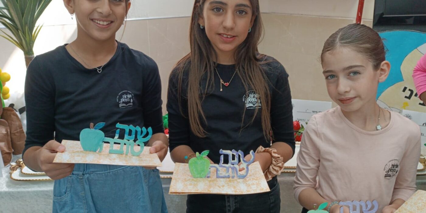 תלמידות מחזיקות בידן יצירה עם הכיתוב שנה טובה