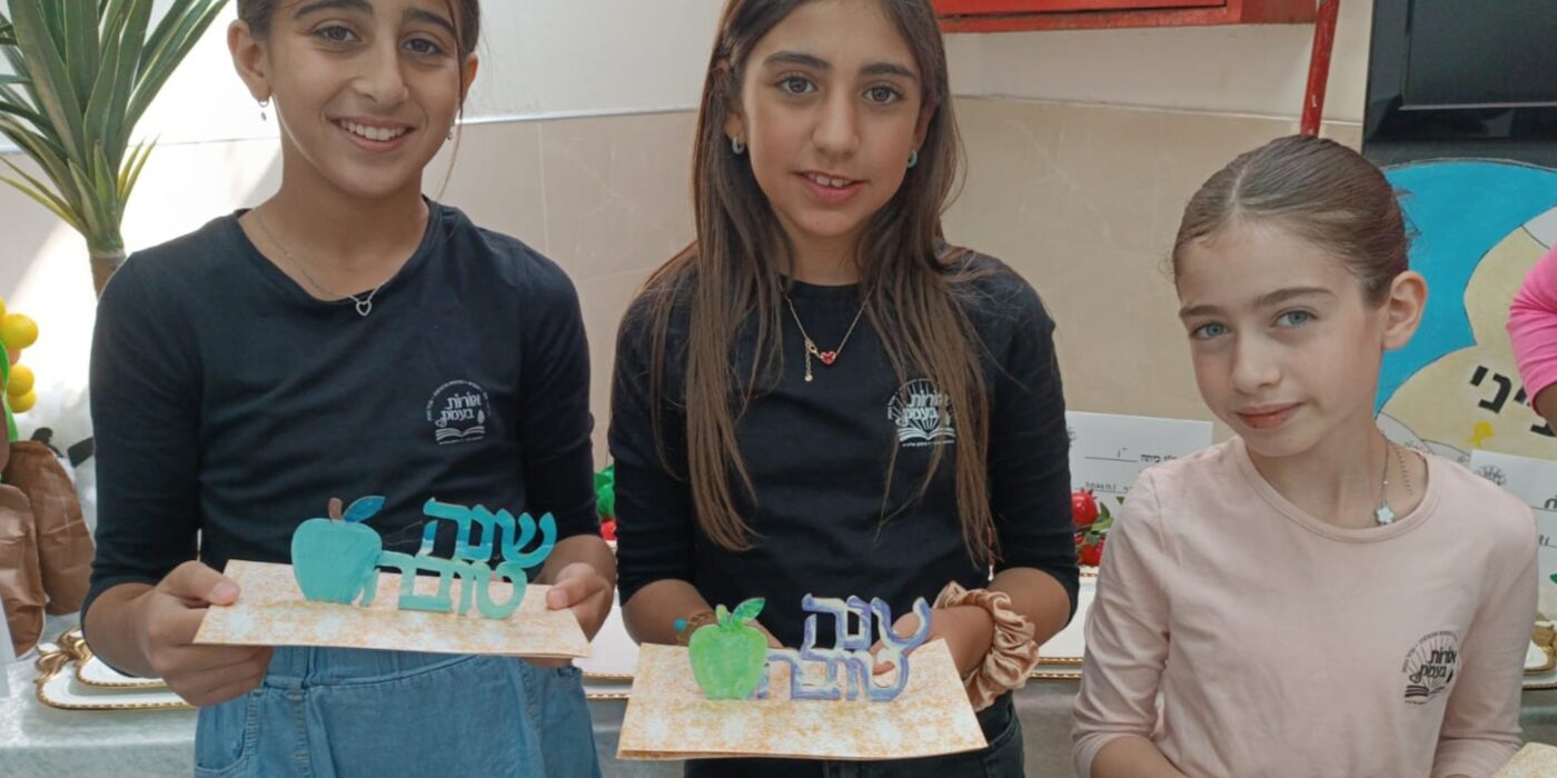 תלמידות מחזיקות בידן יצירה עם הכיתוב שנה טובה