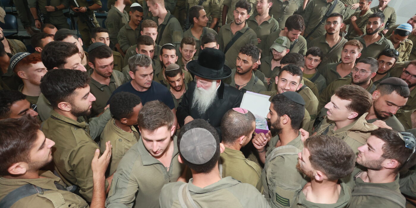 הרב מחלק מטבע למאות חיילים סביבו