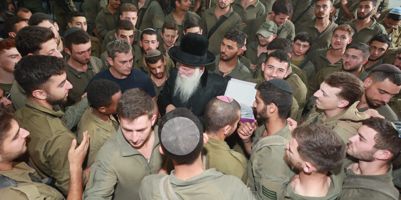 הרב מחלק מטבע למאות חיילים סביבו